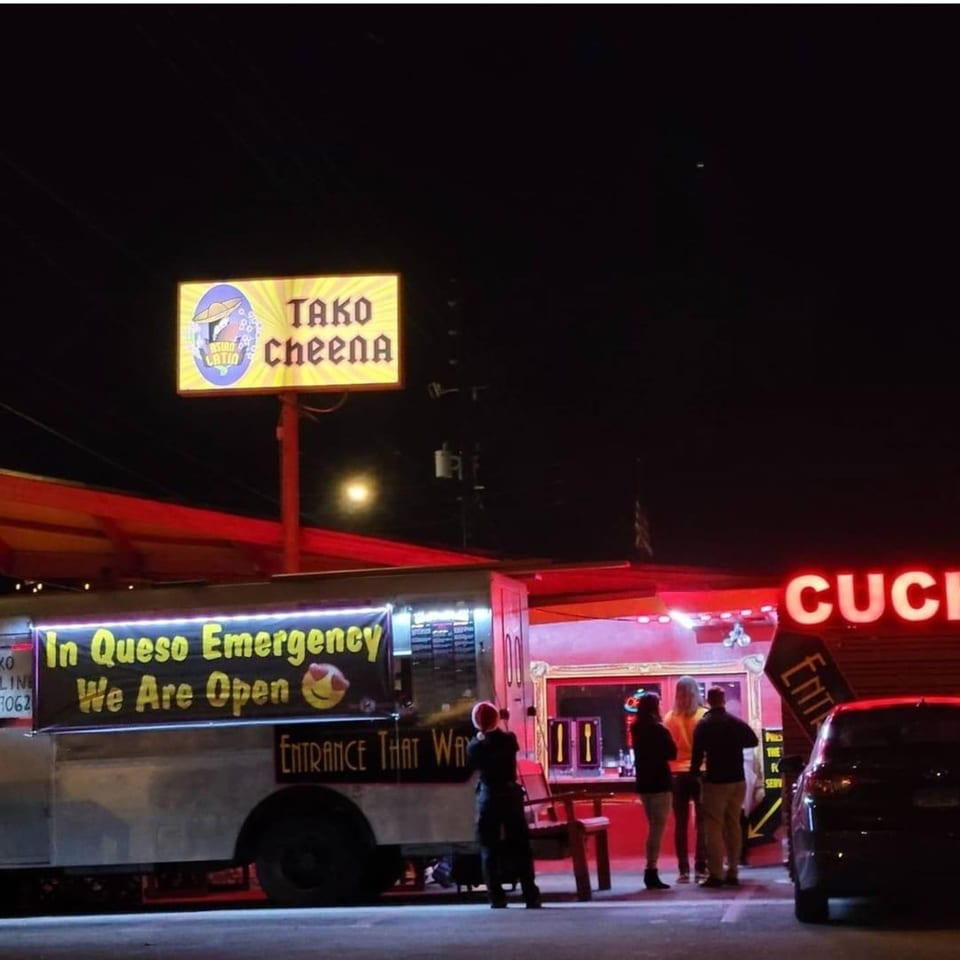 Tako Cheena food truck at night with a bright sign and people standing nearby.