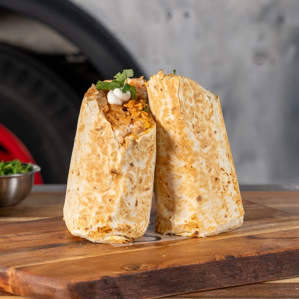 Two large, golden-brown burritos filled with rice and topped with sour cream and cilantro.