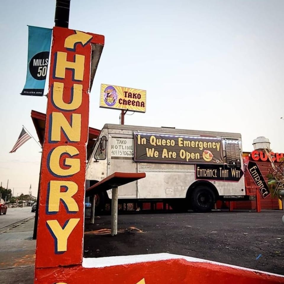 A Tako Cheena food truck with a large red "HUNGRY" sign and a Mills 50 banner.