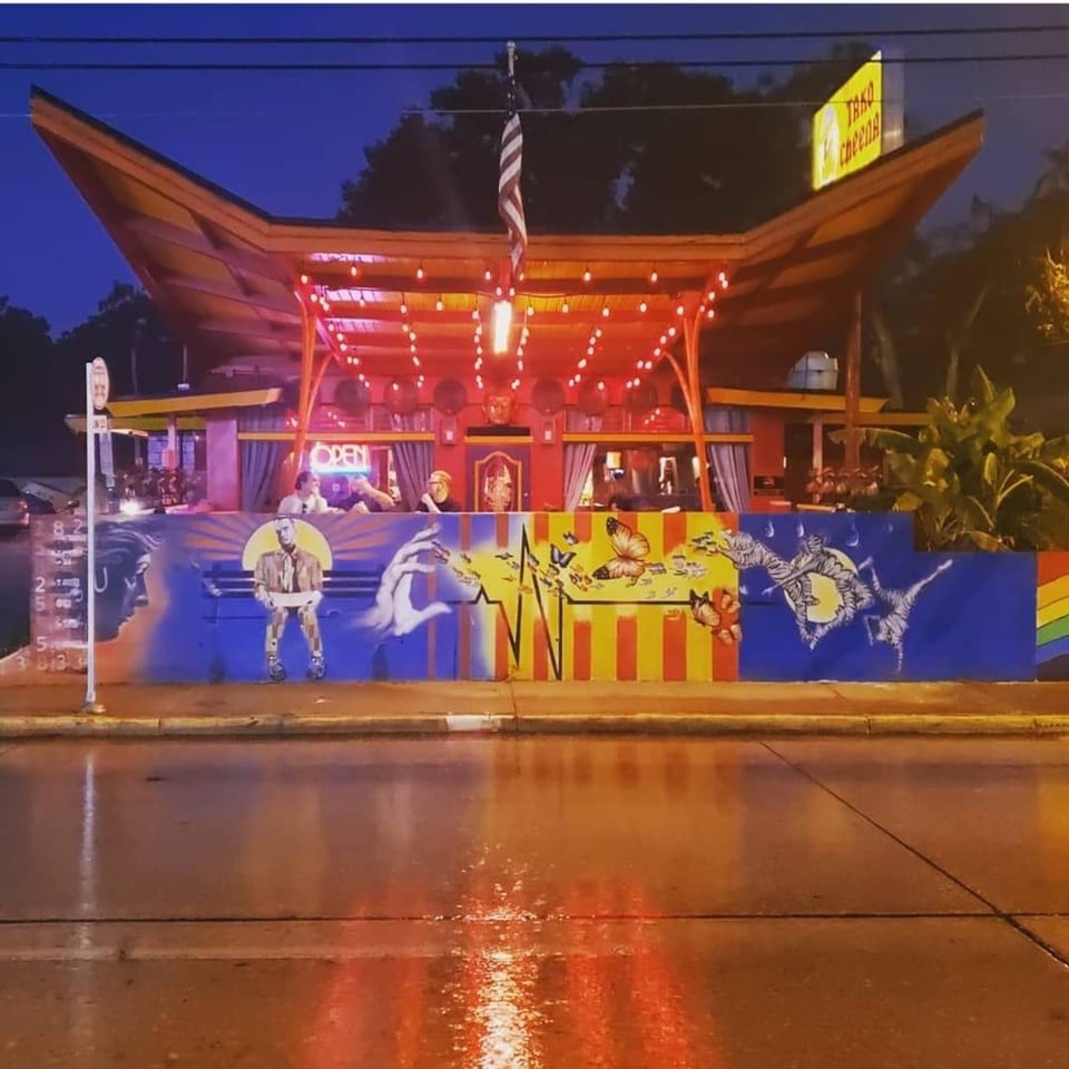 Tako Cheena restaurant at night, with a colorful mural, red lights, and a boat-like roof.