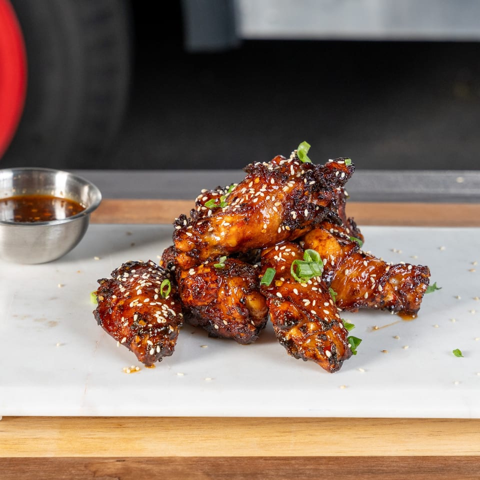 Tako Cheena's Asian-fusion chicken wings, glazed with sauce, sesame seeds, and green onions.